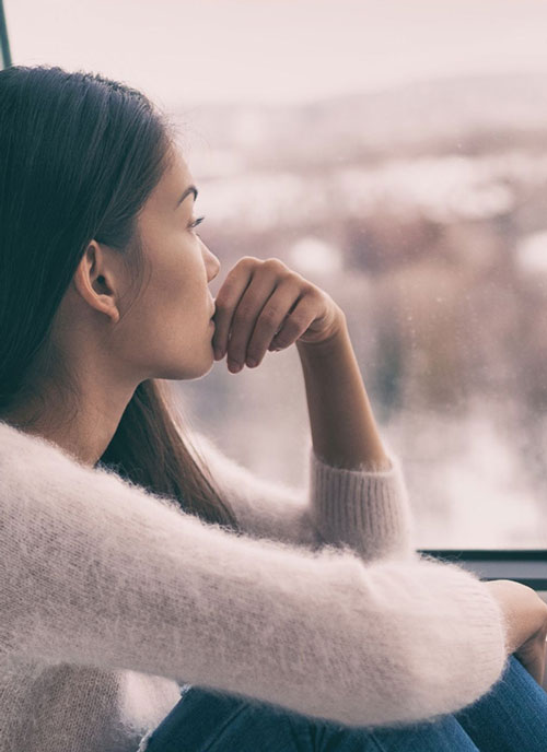 mujer mirando ventana pensando